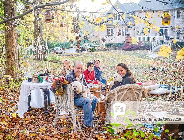 Portrait of mature couple with teenage and adult children picnicing in garden