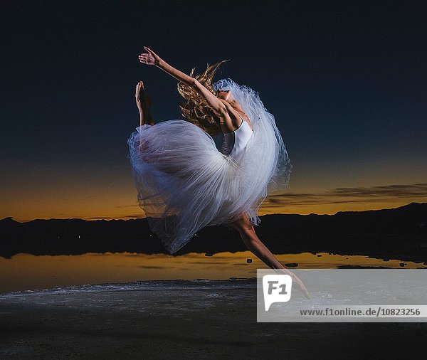 Junge Balletttänzerin beim Sprung über Bonneville Salt Flats in der Abenddämmerung  Utah  USA