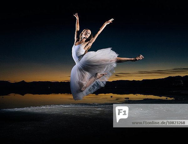 Junge Balletttänzerin beim Sprung über Bonneville Salt Flats bei Sonnenuntergang  Utah  USA