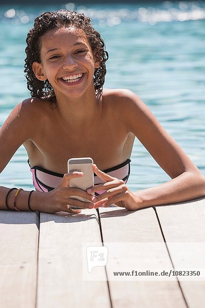Portrait of girl in swimming pool using smartphone