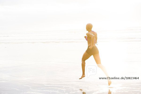 Woman in bikini jogging on beach