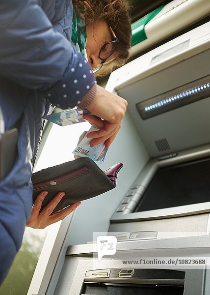Junge Frau mit Geldautomat  Putting Geld in Geldbörse  Untersicht