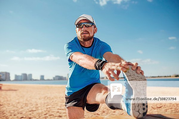 Mittlerer Erwachsener Mann am Strand Bein angehoben  Zehen streckend  Dubai  Vereinigte Arabische Emirate