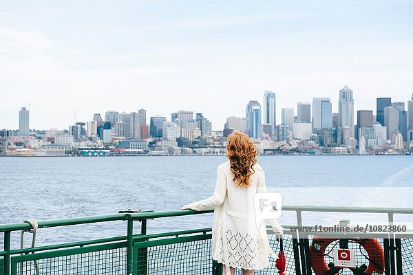 Rückansicht einer Frau  die die Skyline der Stadt von der Passagierfähre auf dem Puget Sound  Seattle  USA  betrachtet.