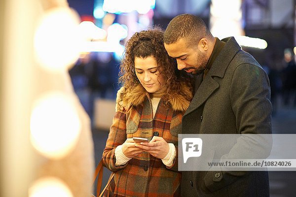 Couple looking at smartphone  outdoors  at night