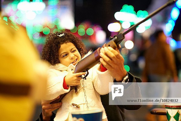 Vater hilft Tochter mit Gewehr im Schießstand auf der Kirmes