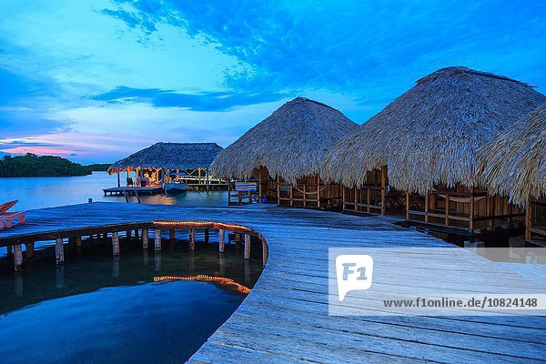 Male tourists in distant waterfront chalet at dusk  St. Georges Caye  Belize  Central America