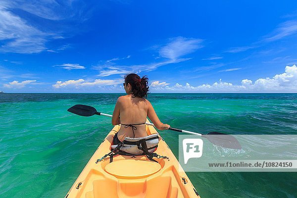 Rear view of woman sea kayaking  St. Georges Caye  Belize  Central America