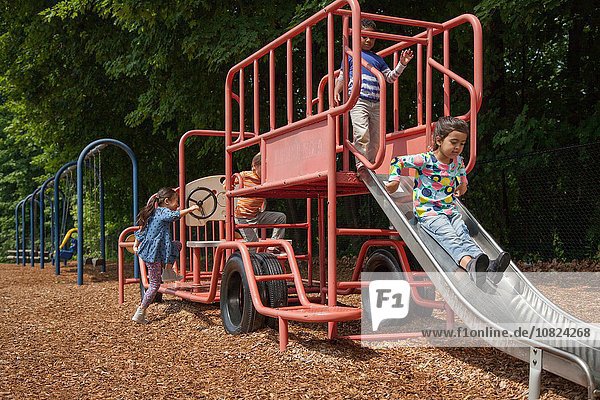 Vier Jungen und Mädchen spielen auf einer Spielplatzschaukel