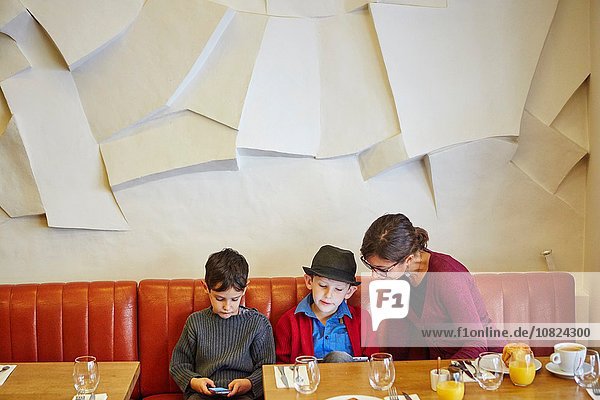 Mutter und Söhne mit digitalem Tablett und Smartphone im Restaurant