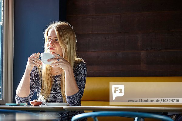 Junge Frau allein im Café beim Kaffeetrinken