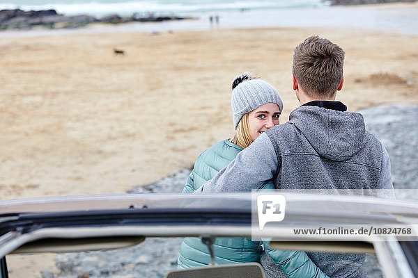 Junges Paar mit Armen umeinander am Strand  Constantine Bay  Cornwall  UK
