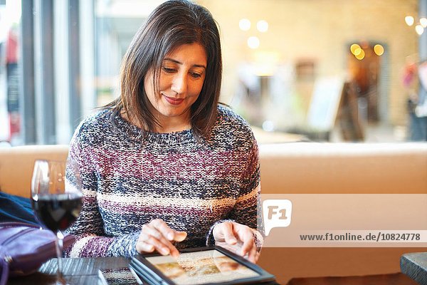 Reife Frau mit Touchscreen auf digitalem Tablett in der Weinbar