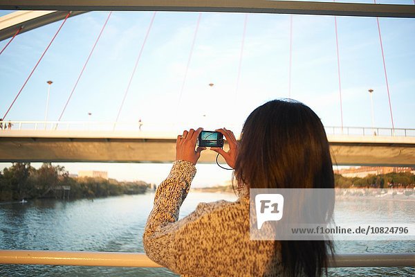 Reife Touristenfotografin am Fluss Guadalqivir mit Digitalkamera  Sevilla  Spanien