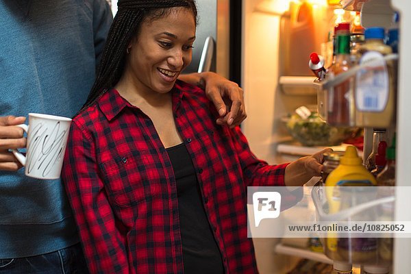 Mid adult couple choosing food from refrigerator in kitchen