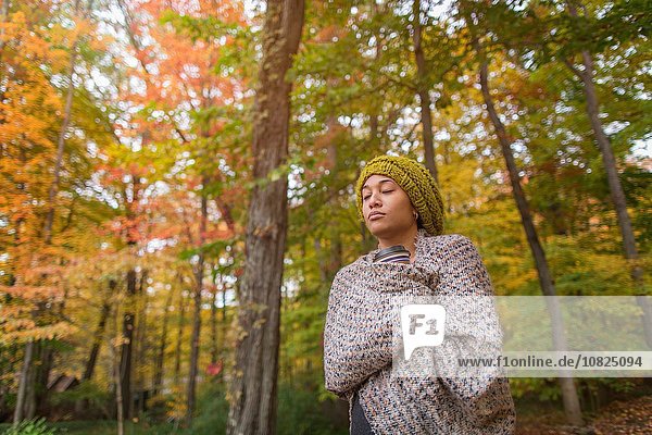 Mittlere erwachsene Frau im Herbstwald in Schal gehüllt