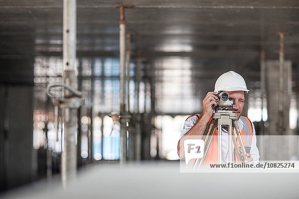 Mid adult male surveyor using theodolite on construction site