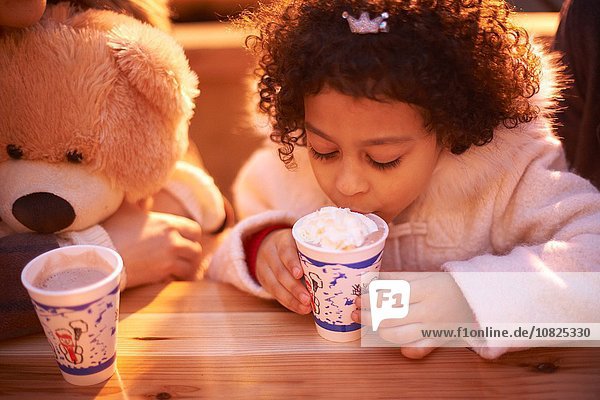 High angle view of girl and teddy bear drinking hot chocolate  looking down