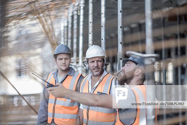 Site manager and builders pointing to steel rods on construction site