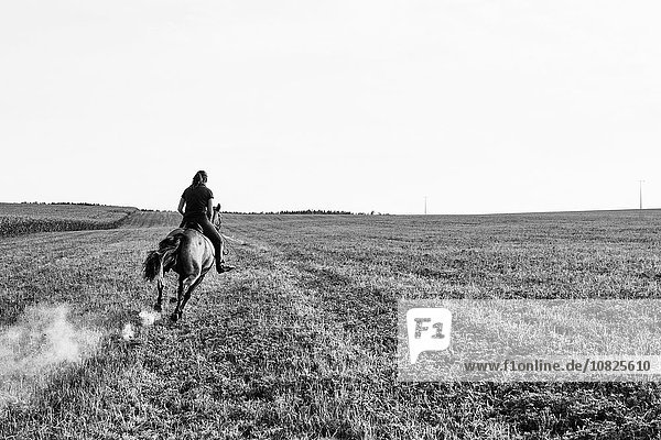 Schwarzweiß-Bild einer Reiterin im Galopp