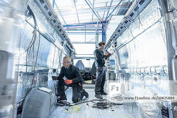 Arbeiter die Elektrik an der Produktionslinie für Reisemobile montieren
