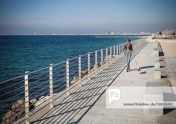 Durchgehende Vorderansicht junge Frau  die am Meer spazieren geht  schaut weg.