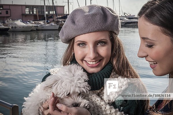 Junge Frau mit Baskenmütze in der Werft  die den Hund hält und lächelnd in die Kamera schaut.