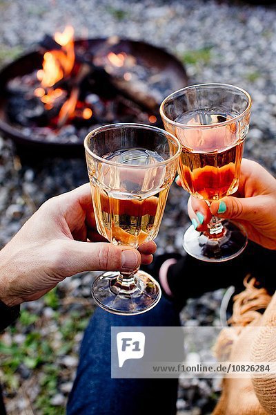 Two people toasting with drinks in wine glasses