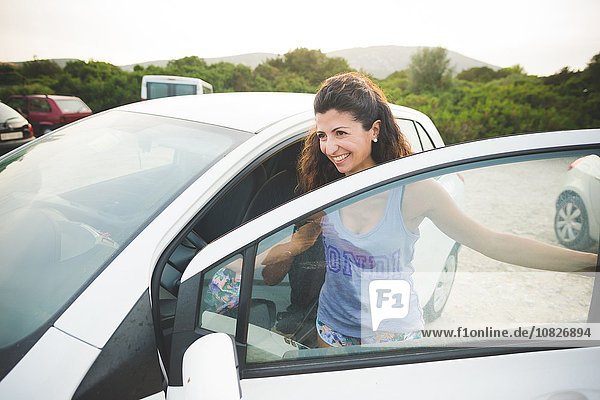 Happy woman getting into car at the coast