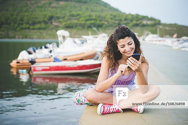 Frau an der Küste Blick auf Smartphone