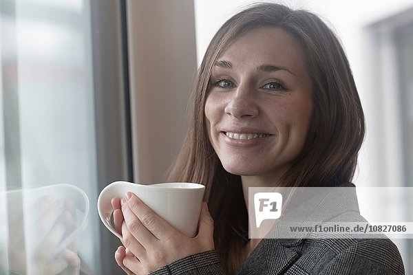 Porträt einer jungen Frau beim Kaffeetrinken im Café