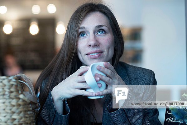 Junge Frau schaut auf  während sie im Café Kaffee trinkt.