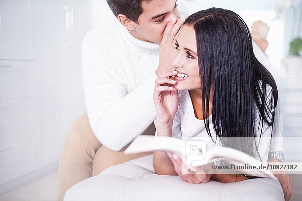 Romantischer junger Mann flüstert der Freundin im Schlafzimmer zu.