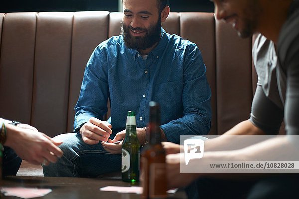 Drei männliche Freunde beim Kartenspielen im traditionellen britischen Pub