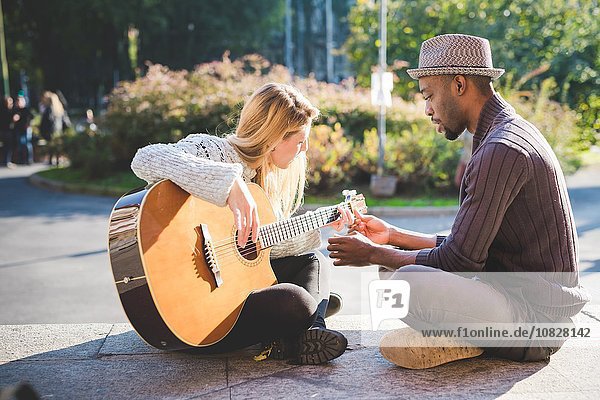 Paar lernt im Park Gitarre spielen