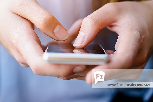 Beschnittene Ansicht von jungen Frauen beim SMSen auf dem Smartphone