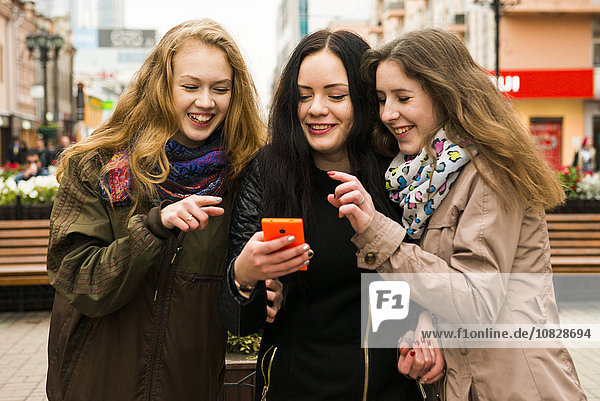 Kaukasische Frauen  die im Freien ein Mobiltelefon benutzen