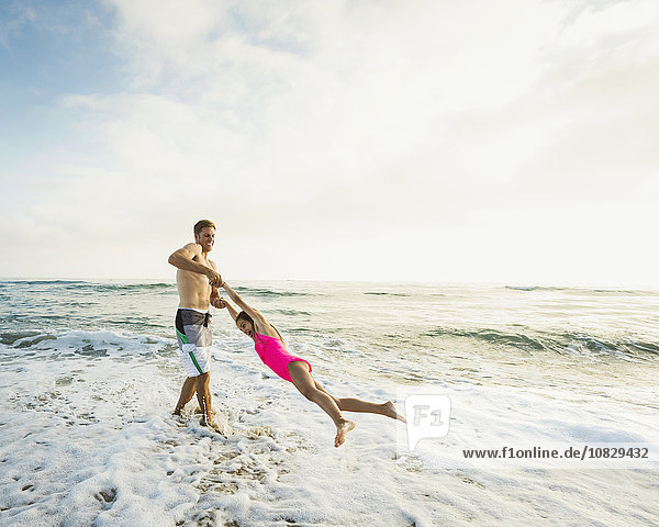 Kaukasischer Vater und Tochter spielen in den Wellen am Strand
