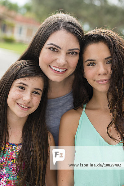 Mother and daughters smiling outdoors
