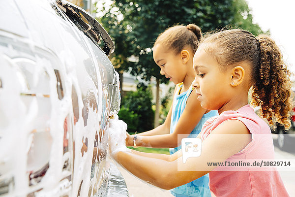 Gemischtrassige Schwestern waschen Auto