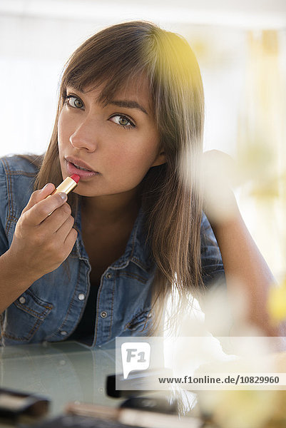 Mixed race woman applying lipstick