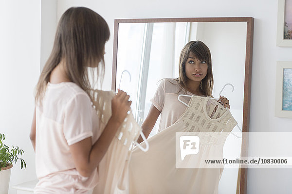 Mixed race woman examining dress in mirror