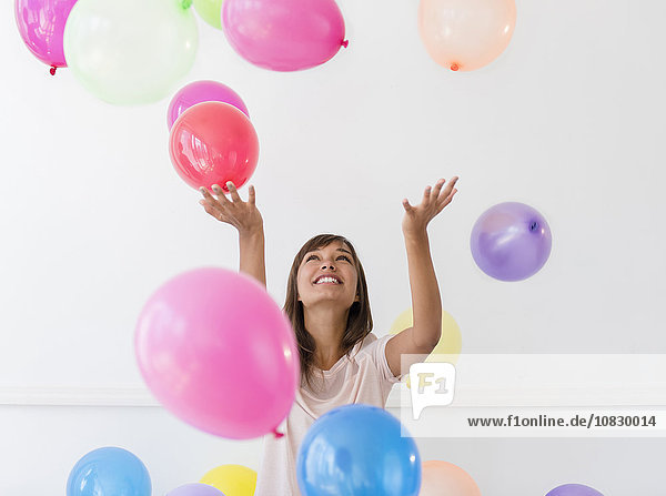 Gemischtrassige Frau spielt mit Luftballons