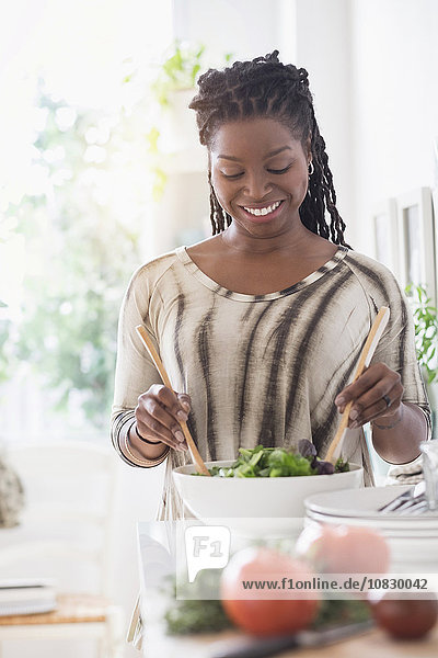 Schwarze Frau  die in der Küche einen Salat zubereitet