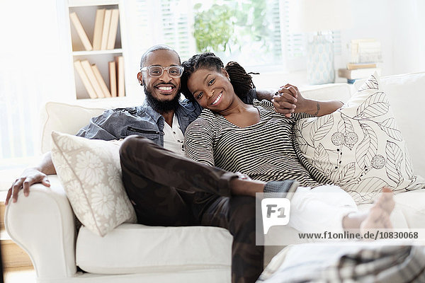 Black couple smiling on sofa