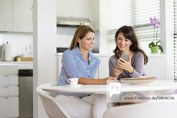 Caucasian women using cell phone in kitchen