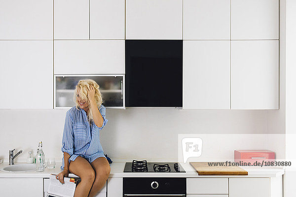 Woman sitting on kitchen counter