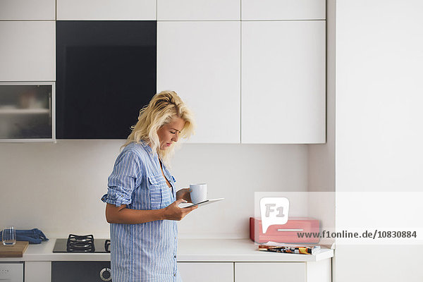 Frau benutzt digitales Tablet in der Küche