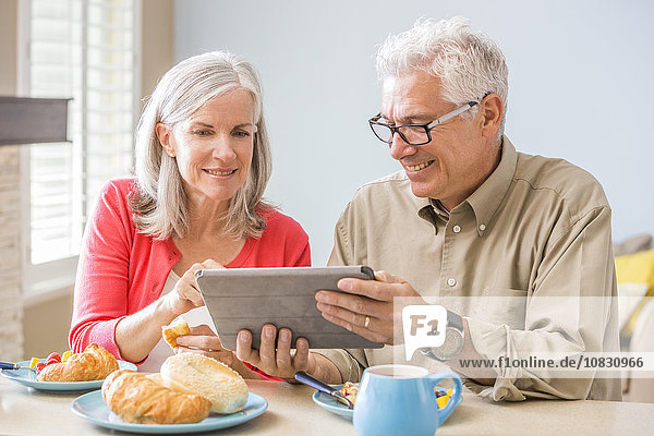 Caucasian couple using digital tablet at table