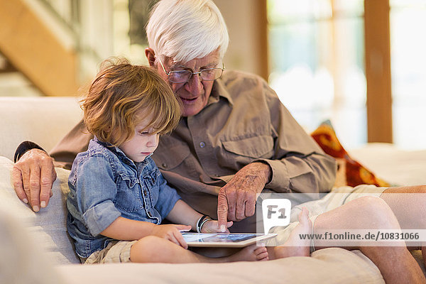 Kaukasischer Großvater und Enkel benutzen ein digitales Tablet